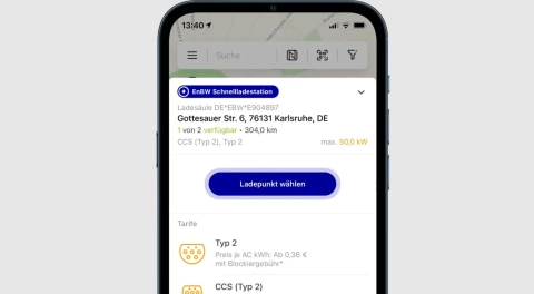 Auf einem Smartphone ist eine App zu sehen, die den nächsten Ladepunkt für das eigene Elektroauto anzeigt.
